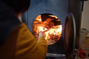 安曇野市にあるAzumino Fukuro Guesthouse - Vacation STAY 21913vの食物をオーブンに入れている人