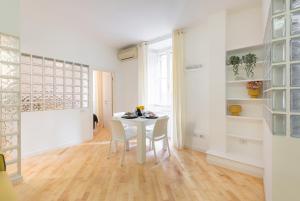 uma sala de jantar branca com uma mesa e cadeiras brancas em VRhome em Roma
