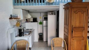una pequeña cocina con electrodomésticos blancos y 2 sillas en Maisonnette Saint-Georges-d'Oléron 17590 à Sauzelle 2 , 3 personnes en Foulerot