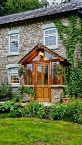 een stenen huis met een houten deur en ramen bij Kingsley Cottage B & B in Beaworthy