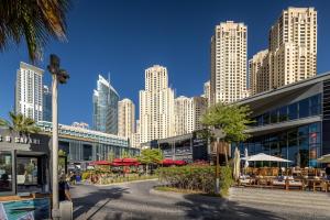 a city with tall buildings and tables and umbrellas at Brand new Rimal 2BD in front of The JBR Beach in Dubai
