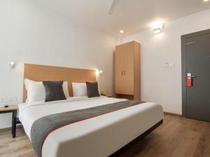 a bedroom with a large white bed with a wooden headboard at Hotel Jaiman in Jaipur