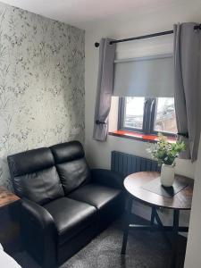 uma sala de estar com um sofá de couro e uma mesa em Woolaway em Taunton