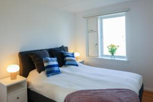 a bedroom with a bed with blue pillows and a window at Penthouse - Amazing views & hygge in Copenhagen