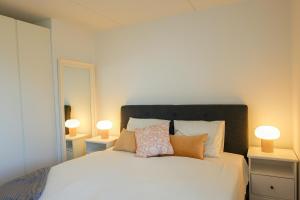 a bedroom with a white bed with two lamps at Penthouse - Amazing views & hygge in Copenhagen