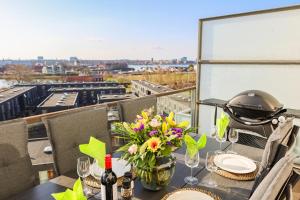una mesa con flores y botellas de vino en el balcón en Penthouse - Amazing views & hygge, en Copenhague