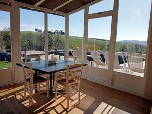 uma sala de jantar com mesa, cadeiras e janelas em Agriturismo Podere il Fornacino em Santa Luce