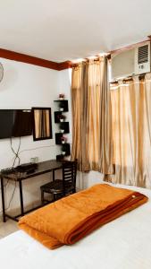 Schlafzimmer mit einem Schreibtisch und einem Bett mit einer Decke in der Unterkunft WHITE HOUSE Luxury Rooms - Loved by Travellers, Couples, Corporates in Jalandhar