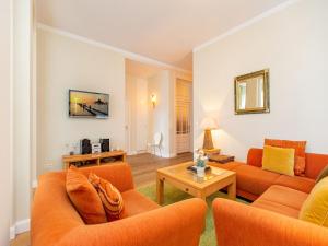una sala de estar con 2 sofás naranjas y una mesa. en Villa Julius App 3 Provence en Heringsdorf