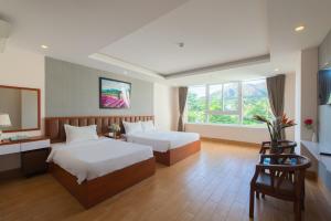 a hotel room with two beds and a television at Canary Nha Trang Hotel in Nha Trang