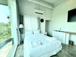 um quarto com uma cama branca e toalhas em Chaisaeng in the park em Ban Tha Ngam