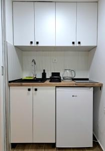 a white kitchen with white cabinets and a sink at Mini duplex apartman in Dušanovac (historical)