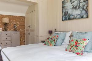 Una cama con sábanas blancas y almohadas en un dormitorio en Old Mill Lodge by Huluki Sussex Stays en Hurstpierpoint