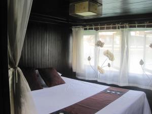 a bedroom with a bed and two windows with white curtains at Cat Ba Boat - Private Boat in Cat Ba