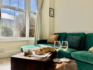 uma sala de estar com um sofá verde e dois copos de vinho em Emerald Lodge Central 3 Bed Parking WI-FI Garden close to centre em Chelmsford