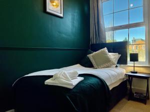Un dormitorio verde con una cama con toallas. en Emerald Lodge Central 3 Bed Parking WI-FI Garden close to centre, en Chelmsford