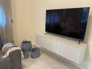 ein Wohnzimmer mit einem Flachbild-TV auf einem weißen Schrank in der Unterkunft MyVilla - Ivrea via Jervis 22b in Ivrea