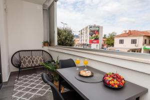 a table with two glasses of wine and fruit on a balcony at Apartman Olimp in Metković