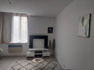 a white living room with a tv and a window at Fresnay-sur-Sarthe: joli appartement au calme. in Fresnay-sur-Sarthe