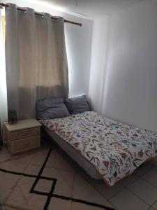 1 dormitorio con 1 cama con cortina y mesa en Fresnay-sur-Sarthe: joli appartement au calme., en Fresnay-sur-Sarthe