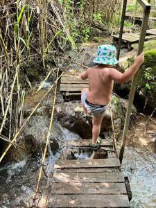 Ein kleiner Junge klettert eine Holzbrücke hoch in der Unterkunft מעיין על הנחל - נופש בקיבוץ in HaGoshrim
