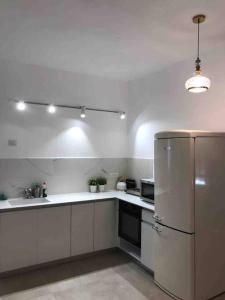 uma cozinha com armários brancos e um frigorífico em מעיין על הנחל - נופש בקיבוץ em Hagoshrim