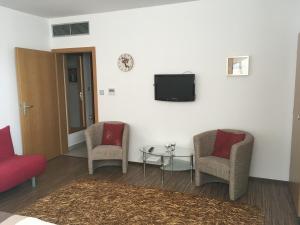 a living room with two chairs and a tv on a wall at Ubytování Pod Borovou in Malenovice