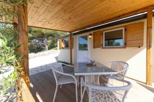 Un patio con una mesa y sillas en una terraza. en Mobilna kuća Lostura 2+1, en Murter