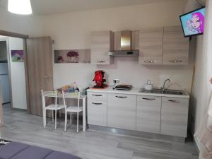 a kitchen with white cabinets and a table and chairs at Villa Rosa B&B Room Vesuvio in SantʼAntonio Abate