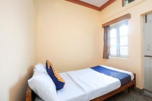 małą sypialnię z łóżkiem z oknem w obiekcie OYO Renuka Lodge w mieście Belagula