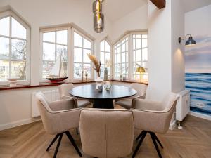 Un comedor con mesa y sillas y ventanas. en Villa Brunnenstraße, App 3, en Heringsdorf