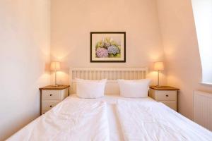 een slaapkamer met een groot wit bed met 2 lampen bij Villa Frohsinn App 15 in Bansin