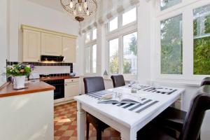 cocina con mesa blanca, sillas y ventanas en Villa Hartmann Drewitz, App 06, en Heringsdorf