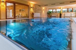 a large swimming pool with blue water in a building at Simon - das Vitalhotel in Bad Tatzmannsdorf