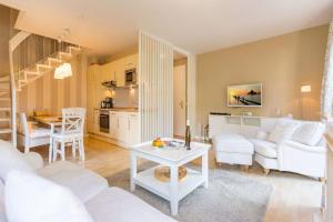 ein Wohnzimmer mit weißen Möbeln und eine Küche in der Unterkunft Haus auf dem Hügel, Die Moderne 12 in Bansin