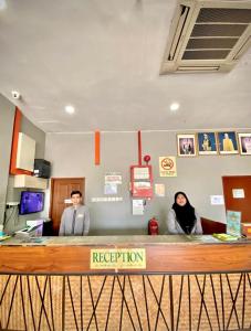 two people sitting at a reception desk in an office at Langgura Baron Resort in Pantai Cenang