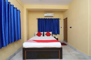 um quarto com uma cama grande e cortinas azuis em OYO Maa Tara Guest House Near Acropolis Mall em Jādabpur