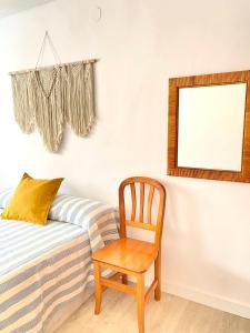 a chair next to a bed with a mirror at Apartamento en playa de Altafulla in Altafulla