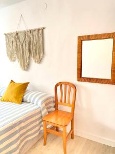 a chair next to a bed with a mirror at Apartamento en playa de Altafulla in Altafulla +18 photos