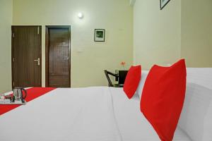ein Schlafzimmer mit einem großen weißen Bett mit roten Kissen in der Unterkunft OYO Tableau Homestay in Kandāghāt