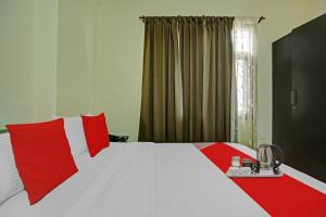 ein Schlafzimmer mit einem großen Bett mit roten Kissen in der Unterkunft OYO Tableau Homestay in Kandāghāt
