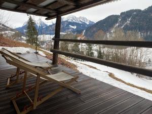 a rocking chair on a deck with a view of mountains at Heidi Chalet in Rossinière