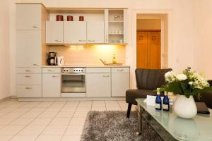 una cocina con armarios blancos y una mesa con un jarrón de flores en Villa Medici Heringsdorf App 07, en Bansin