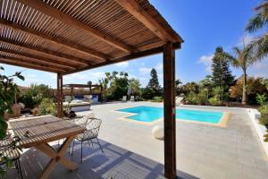 un patio con una pérgola de madera y una piscina en No 23, Bali House, en Lajares