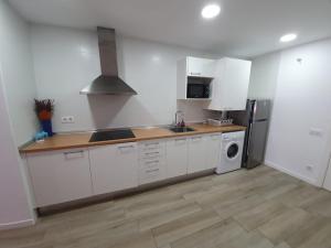 a kitchen with white cabinets and a sink and a refrigerator at Amadeu 1, Calella in Calella