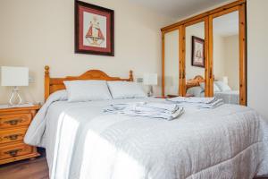 a bedroom with a bed with white sheets and a mirror at Apartamentos La Cortina in Cangas de Onís