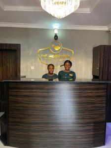 dos hombres parados detrás de un bar en un restaurante en The Moonshine Residence-Royal, en Nnewi