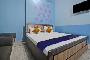 SPOT ON Hotel Rj14 في جايبور: غرفة نوم مع سرير وتلفزيون على الحائط