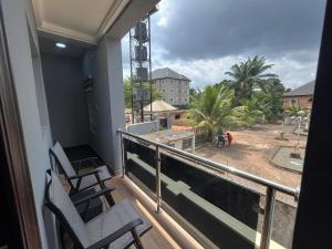 balcón con 2 sillas y vistas a un patio en The Moonshine Residence-Royal, en Nnewi