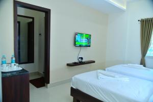 a hotel room with two beds and a tv on the wall at RK COMFORTS in Bengaluru